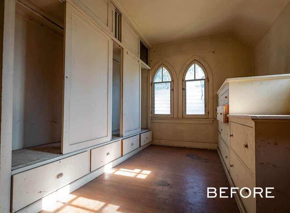 Old dressing room with built-in cabinets, worn wood floors, and arched windows