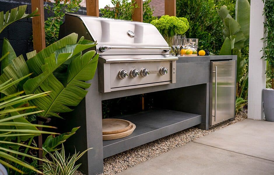 Outdoor kitchen with a stainless steel grill, a concrete countertop, and a built-in refrigerator