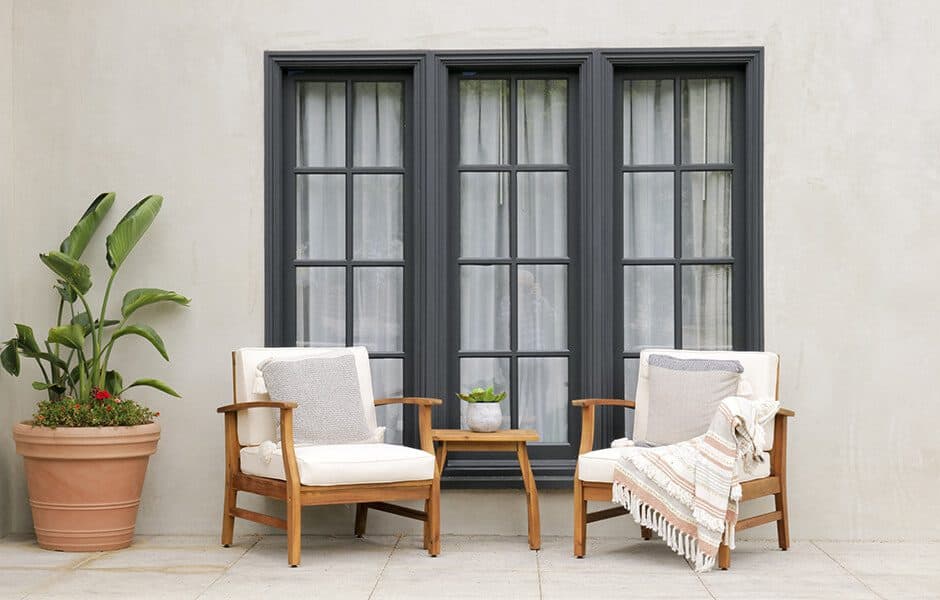 Two wooden armchairs with white cushions and a small table on a patio