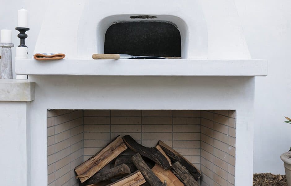 White outdoor fireplace with wood storage and pizza oven