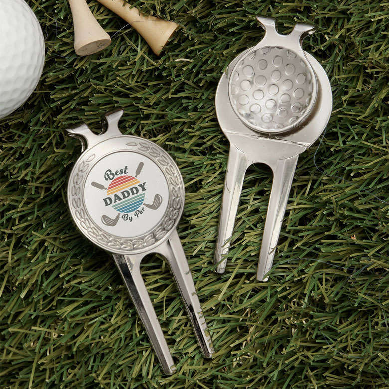 Silver golf divot tools with circular markers, one reading “Best Daddy by Par” with golf club graphics