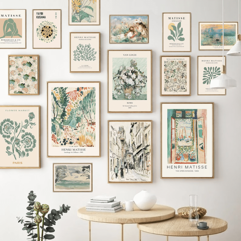 Artistic gallery wall with framed botanical and impressionist prints above wooden nesting tables with decor