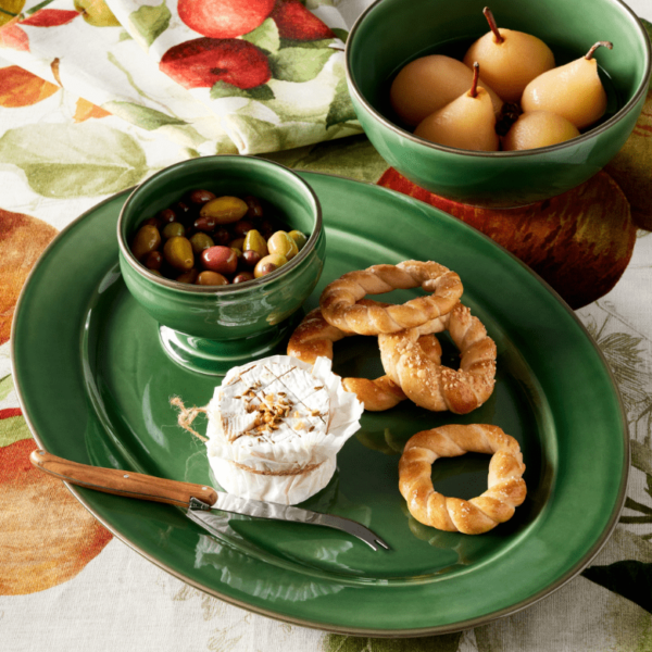 Green platter with brie, olives, pretzels, and a bowl of poached pears