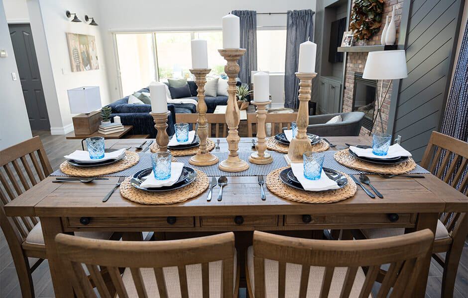 Elegant dining table with wooden chairs, candles, and blue glassware in a modern space