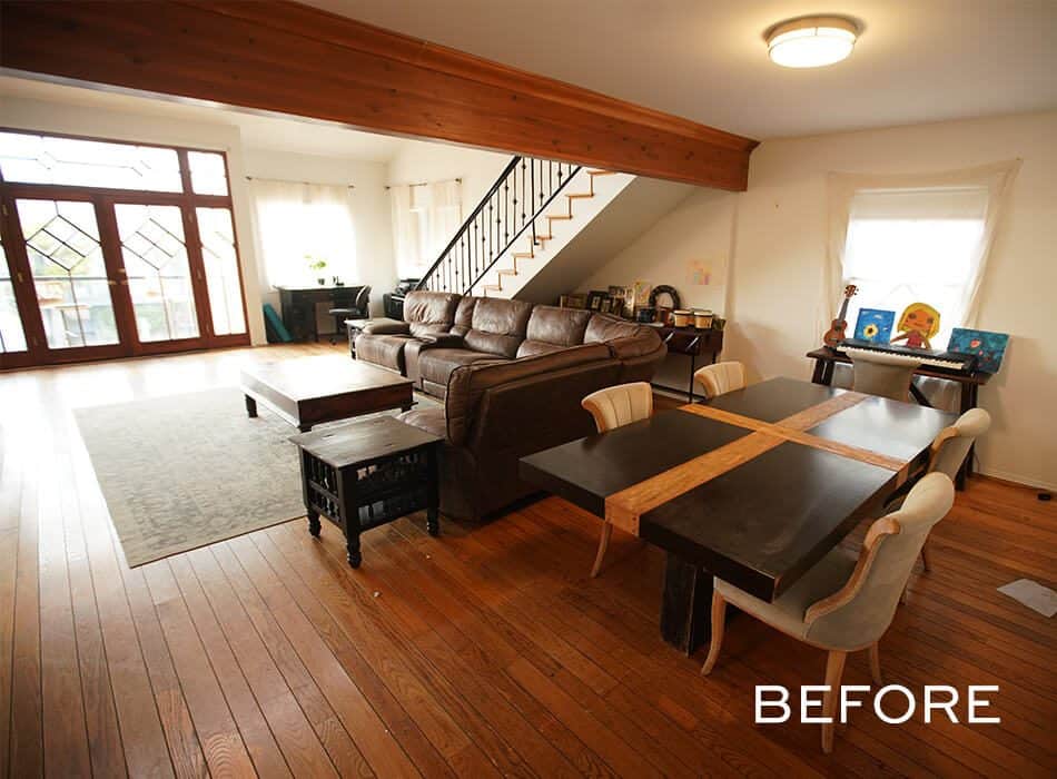 Open-plan room with wood floors, brown sofa, black dining table, and staircase