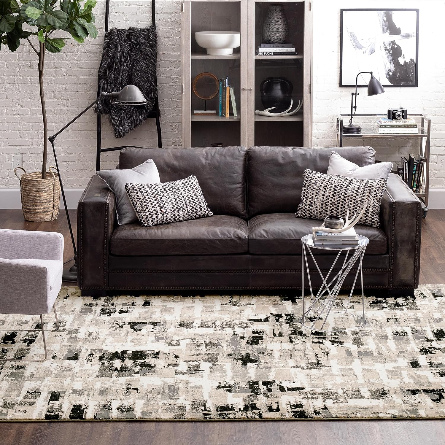 Contemporary living room with a dark leather sofa, patterned rug, and minimalist decor