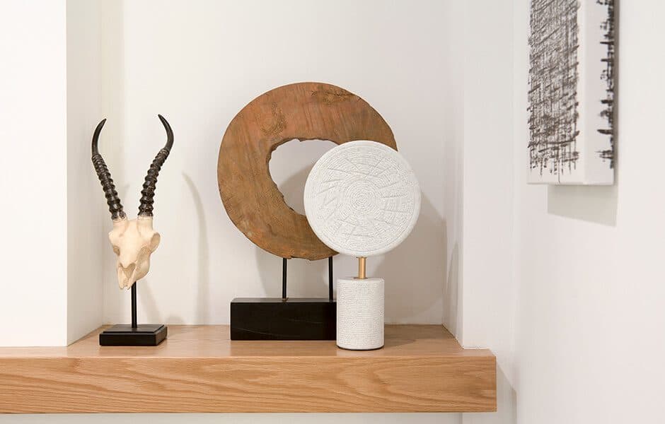 Decorative shelf with horn sculpture, wooden circle art, and textured white sculpture