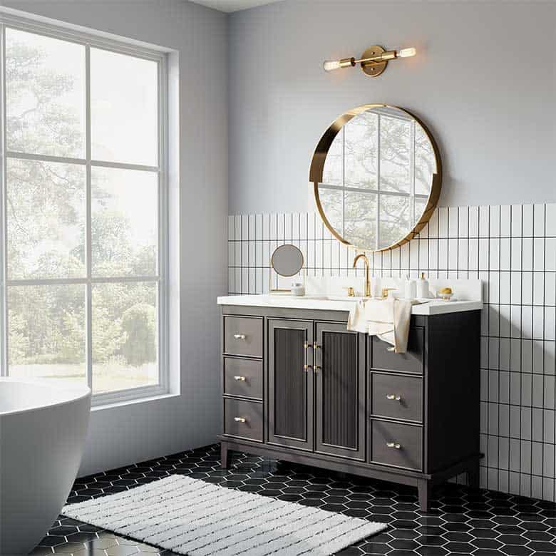 Bathroom with black vanity, gold round mirror, white tile backsplash, and black hexagon floor tiles