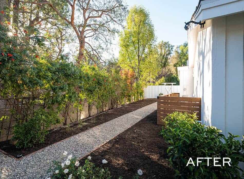 Backyard with gravel walkway, fresh landscaping, wooden planter boxes, and white fence