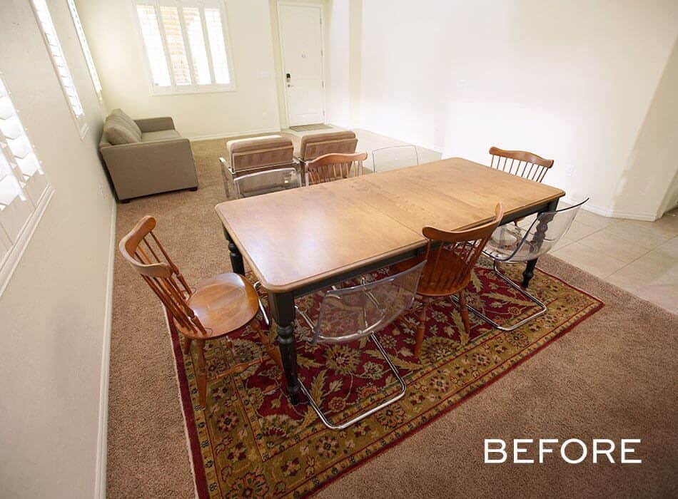 Dining area with mixed chairs, a wooden table, and a red patterned rug before renovation