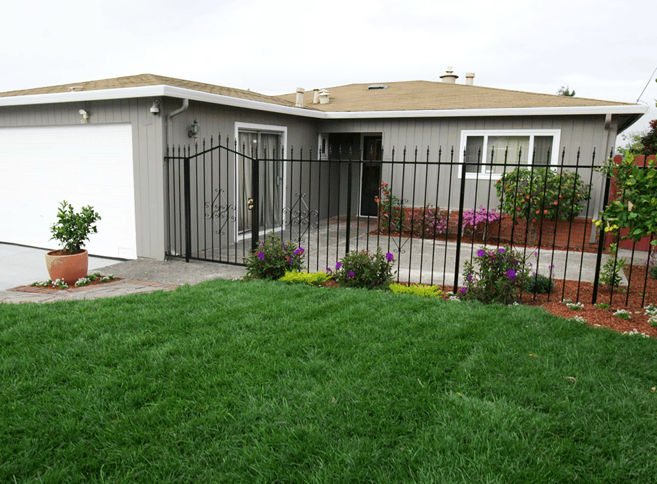 Suburban home with a green lawn, colorful flowers, and a concrete patio