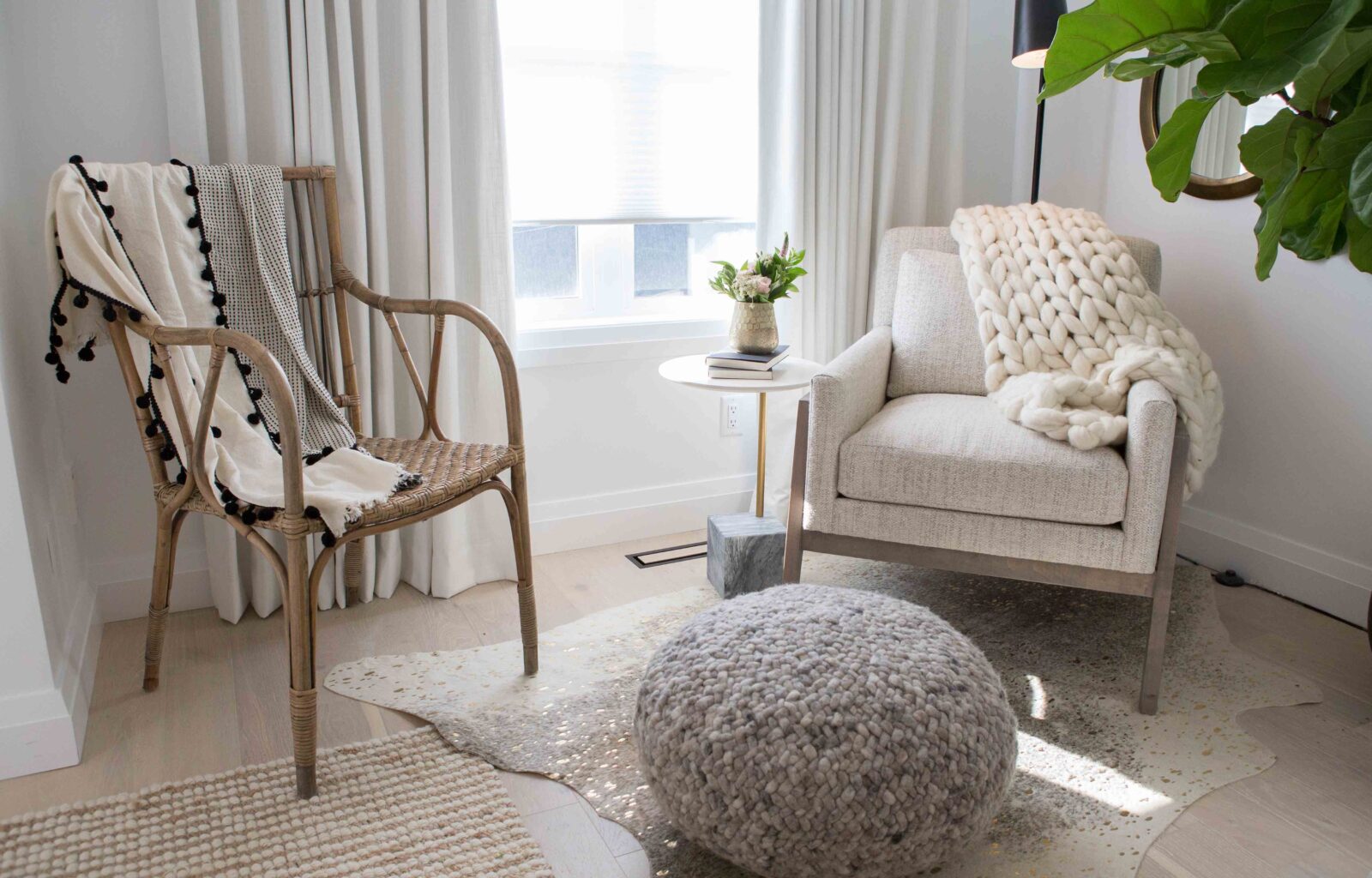 Cozy reading nook with rattan chair, upholstered armchair, knitted pouf, and soft neutral decor