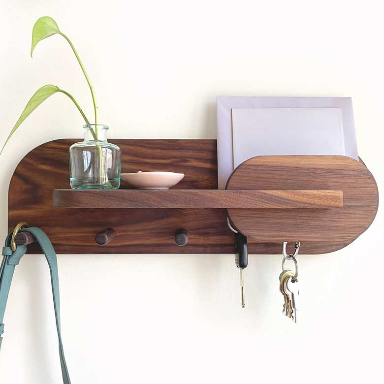 Wooden wall organizer with hooks, mail slot, keys, a small glass vase, and a ceramic dish