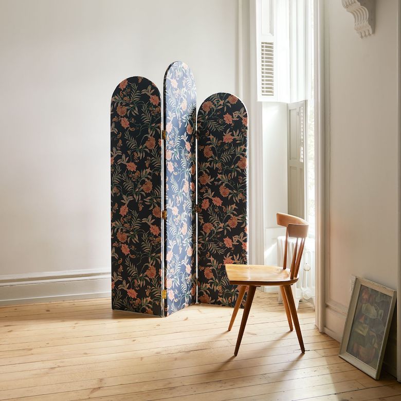 Minimal room with a floral folding screen, wooden chair, and light wood flooring near a tall window