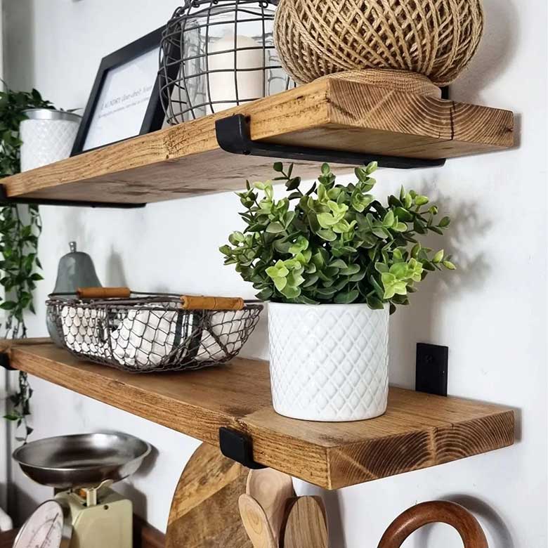 Wooden wall shelves with black metal brackets, decorated with a potted plant, wire baskets, candle, and twine ball