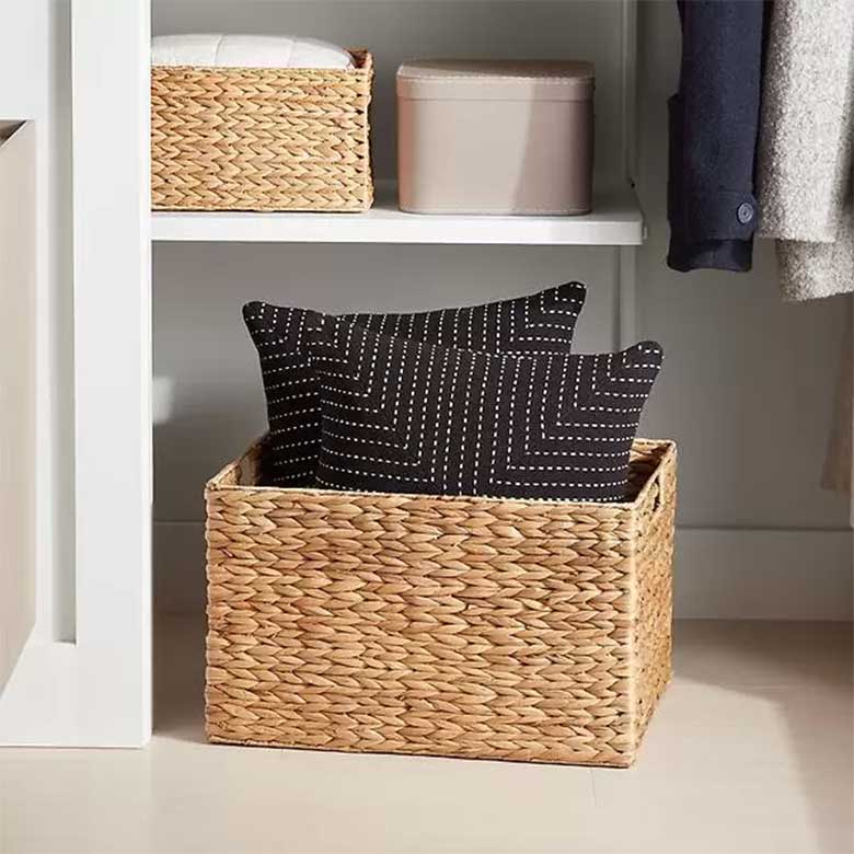 Two black embroidered pillows sitting inside a woven storage basket