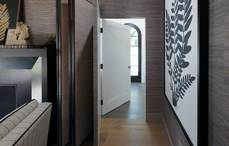Elegant hallway with textured walls, botanical artwork, and an arched doorway in the background