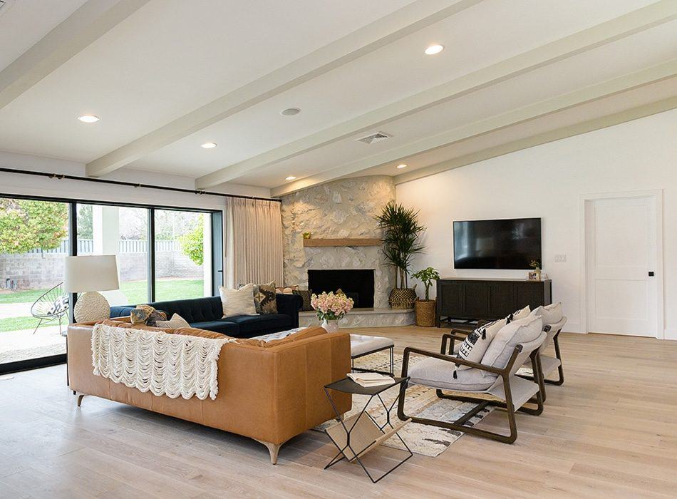 Spacious living room with a stone fireplace, brown leather sofa, and large sliding glass doors