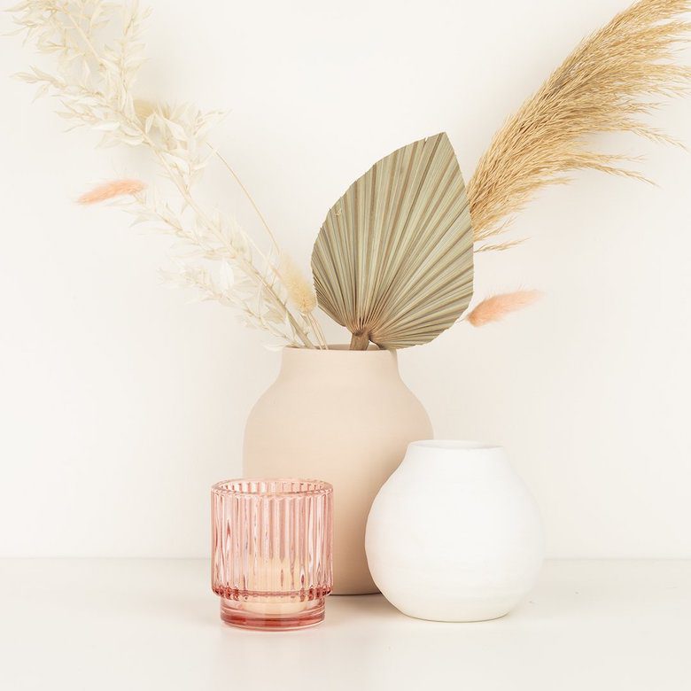 Neutral-toned vases with dried pampas grass, palm leaf, and pink glass candle holder