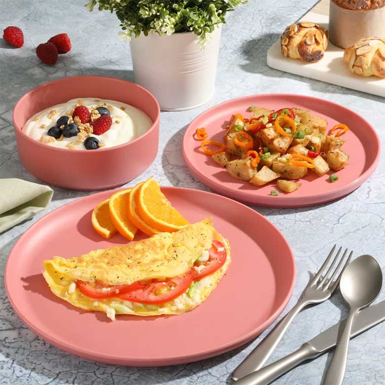 Breakfast with omelet, potatoes, and yogurt served on pink dishes