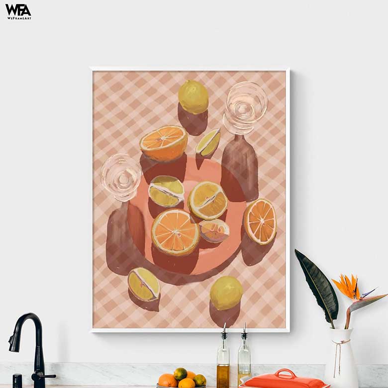 Framed artwork of sliced citrus fruits on a checkered background, displayed above a modern kitchen counter with decor