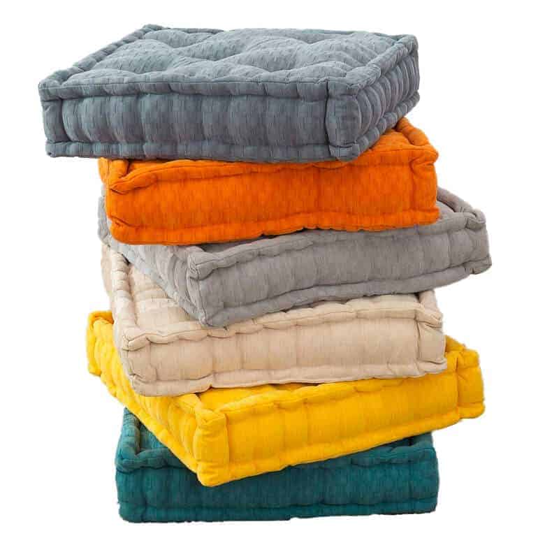 Stack of colorful square floor cushions in shades of blue, orange, gray, beige, yellow, and teal