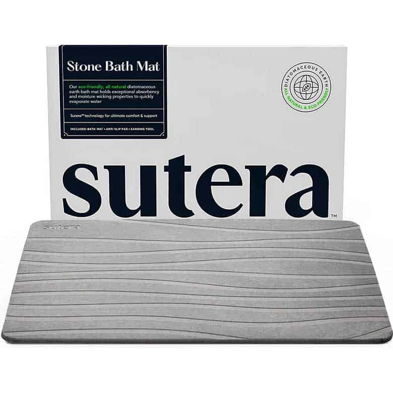 Gray Sutera stone bath mat with textured surface, shown in front of product packaging