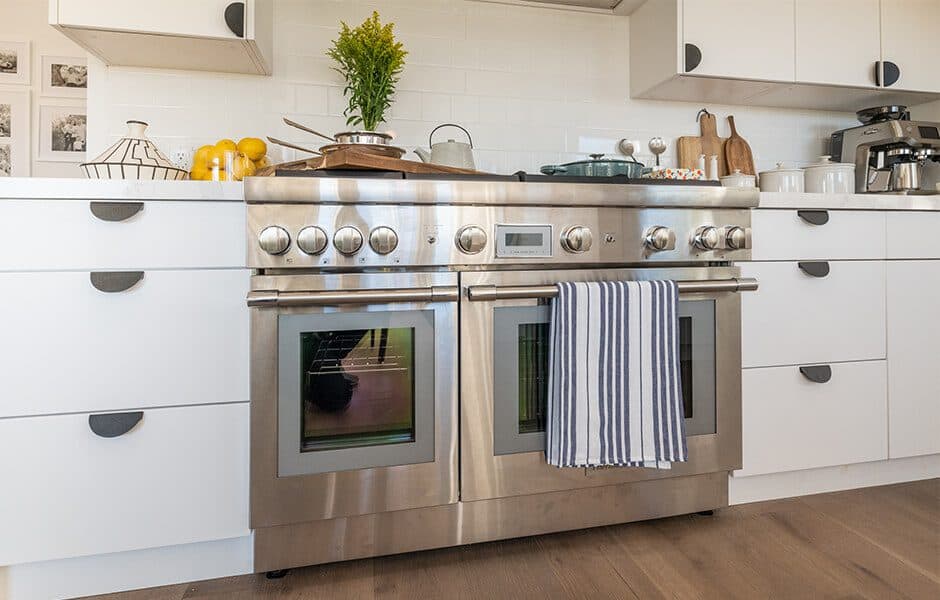 Modern kitchen with a stainless steel oven, white cabinets, and decorative accents