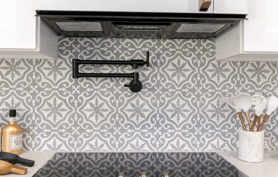 Gray and white patterned kitchen backsplash with a black pot filler faucet