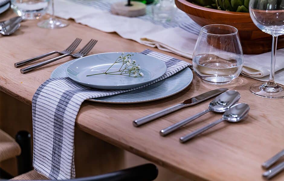 Elegant table setting with striped napkin, glassware, and silverware on wooden table