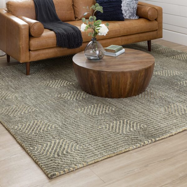 Cozy living room with a geometric-patterned rug, round wooden coffee table, and tan leather sofa
