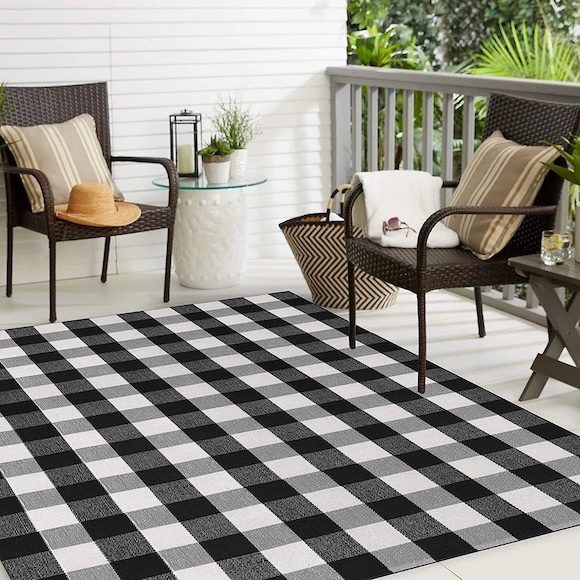 Cozy patio with wicker chairs, striped pillows, and a black-and-white checkered outdoor rug.