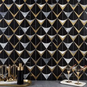 Black, white, and gold geometric patterned tile backsplash with a bar setup featuring cocktails and accessories
