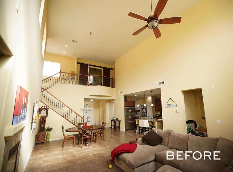 Spacious living room with high ceilings, beige walls, sectional sofa, dining area, and staircase