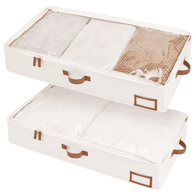 Two beige under-bed storage bags with brown handles and clear zippered tops, holding folded blankets and linens