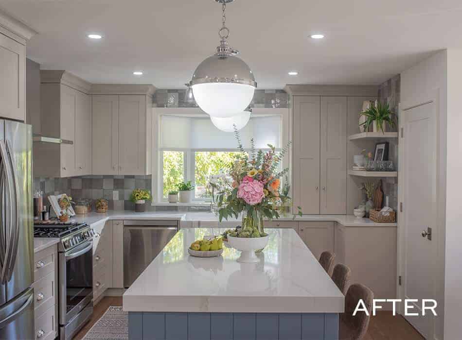 A renovated kitchen with gray cabinets, a patterned backsplash, and fresh flowers on the island