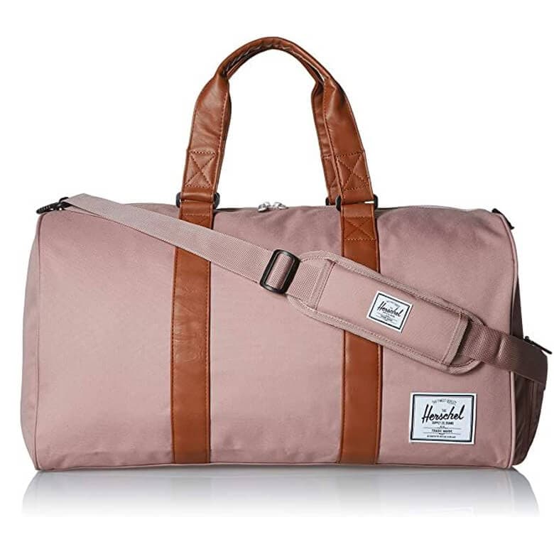 Pink duffel bag with brown leather accents and an adjustable shoulder strap