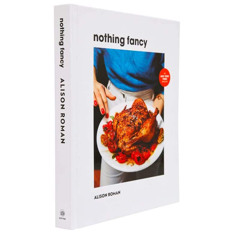 "Nothing Fancy" cookbook by Alison Roman, featuring a cover image of a roast chicken with tomatoes on a white plate