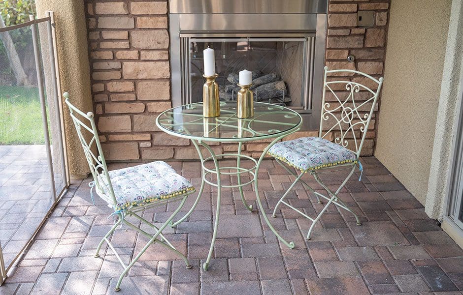Outdoor patio with a glass table, two metal chairs, and candles
