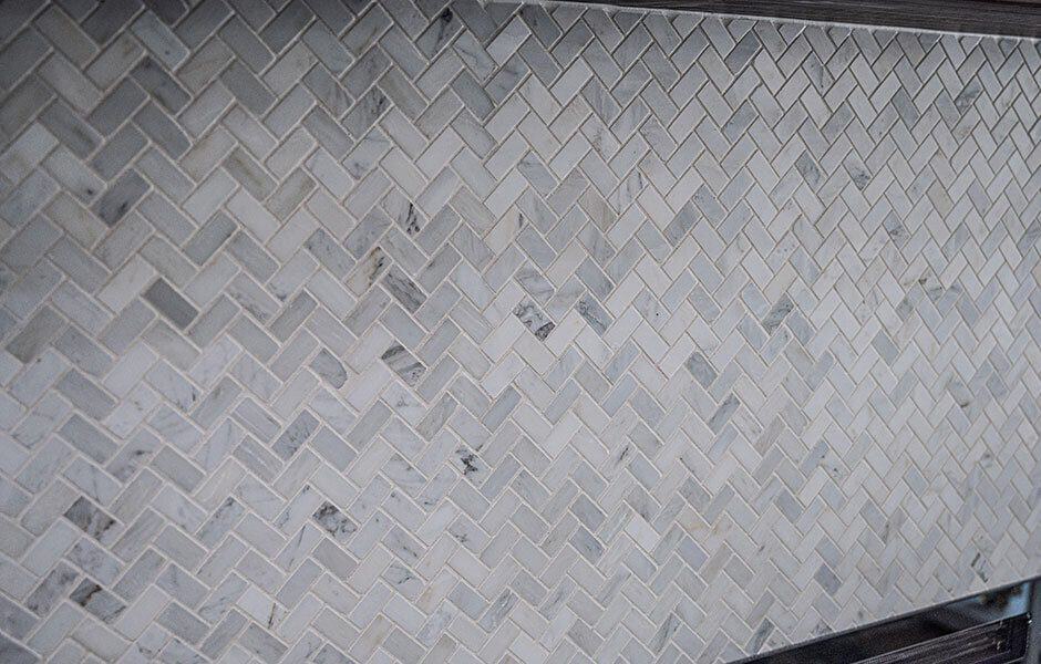 Close-up of herringbone-patterned marble tile backsplash