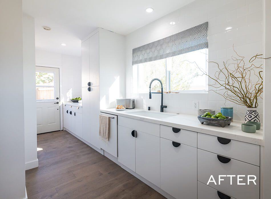 Image of a renovated kitchen with white cabinets, white countertops, and a black faucet