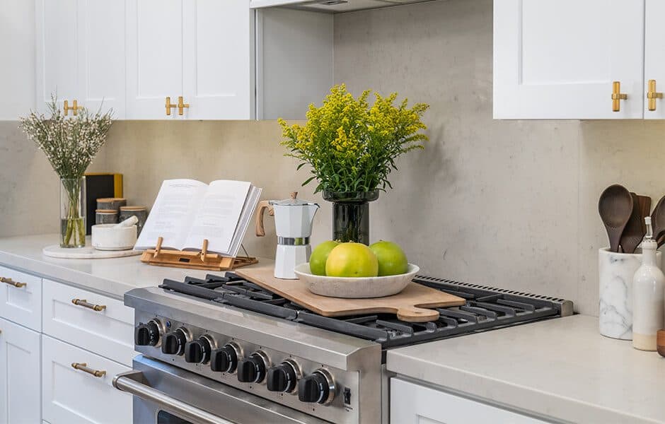 Kitchen with white cabinets, gold hardware, a gray quartz countertop and a stainless steel gas range