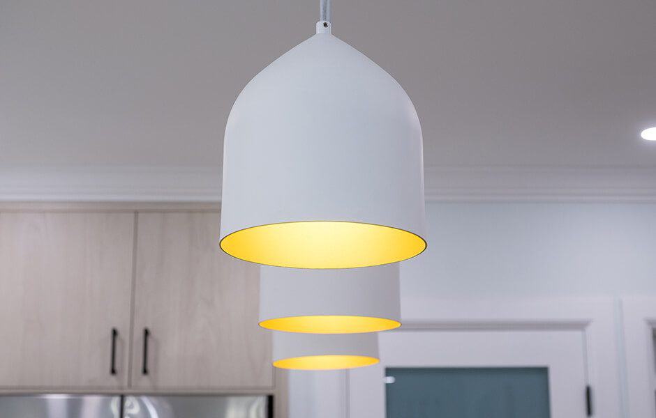 Close-up of modern white pendant lights with a warm yellow glow inside, hanging in a kitchen