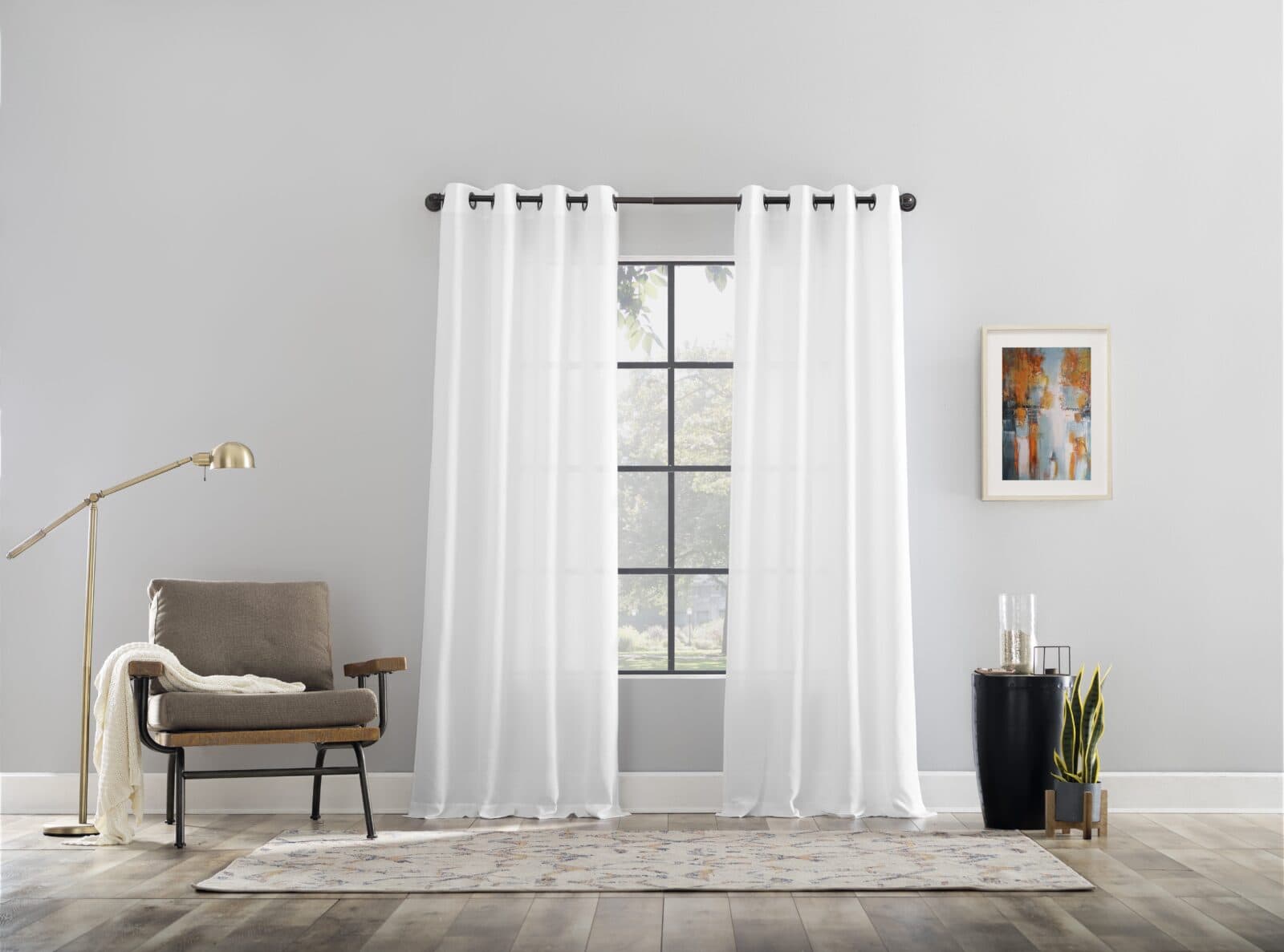 Minimalist living space with sheer white curtains, a cozy armchair, and modern decor