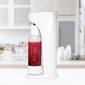 White soda maker with a transparent bottle filled with red sparkling beverage, set in a modern kitchen