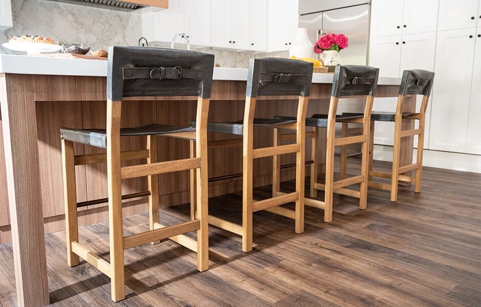 Kitchen island with wooden bar stools featuring black leather backrests and seat cushions