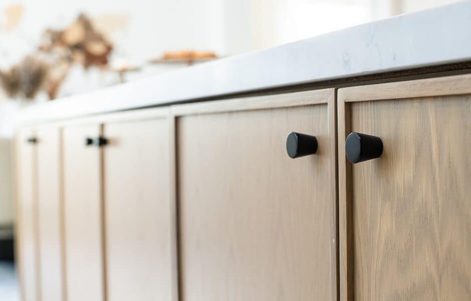 Close-up of light wood cabinets with black knobs and a white countertop