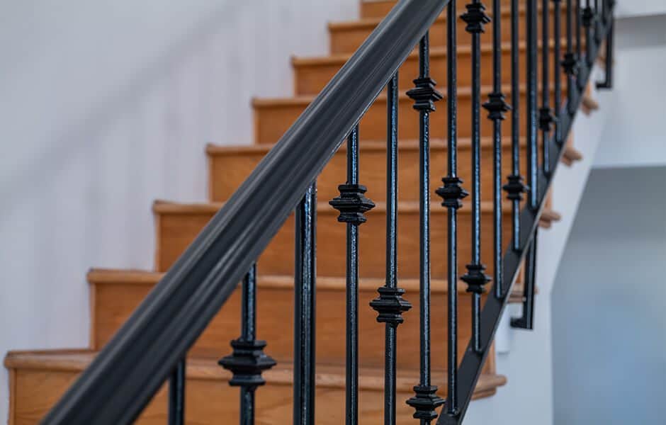Close-up of a wooden staircase with decorative black metal railings