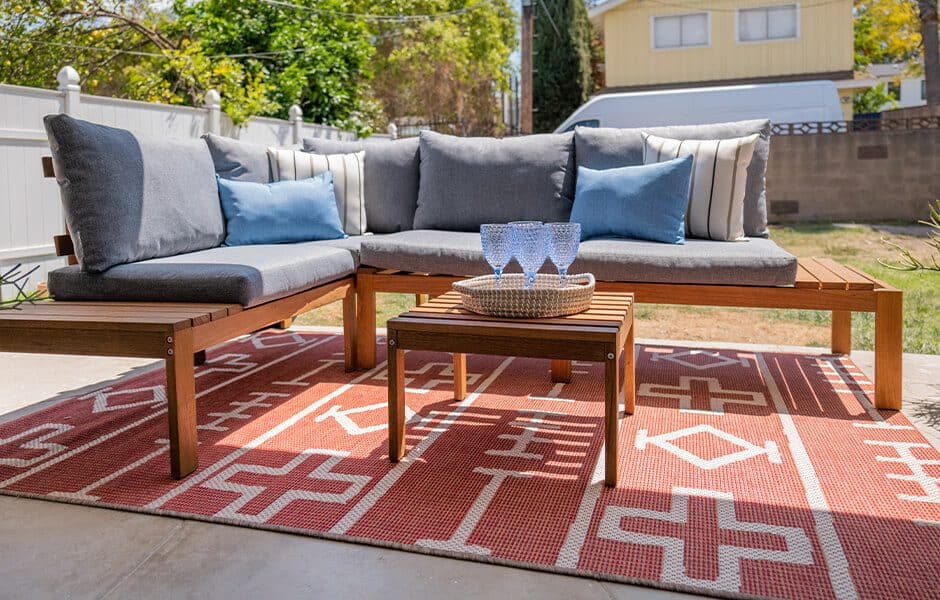 Wooden sectional sofa with gray cushions and blue throw pillows, together with a small coffee table