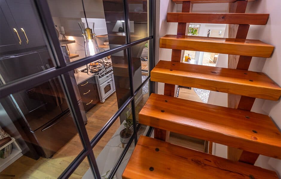 Wooden staircase with glass window overlooking kitchen